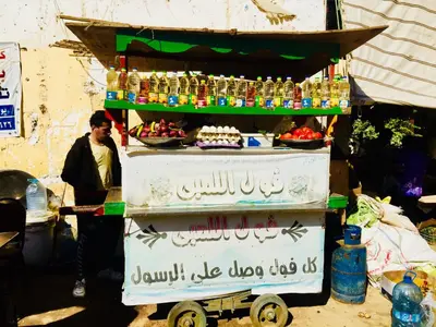 a man standing next to a food stand with drinks at Zebra Apartments Hurghada center in Hurghada