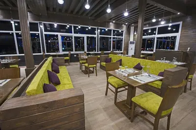 a restaurant with yellow seats and tables and windows at Sunrise Royal Makadi Resort in Hurghada