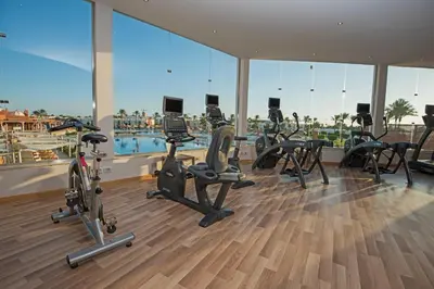 a gym with cardio equipment in a building with a view at Sunrise Royal Makadi Resort in Hurghada