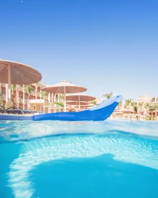 a swimming pool with blue water and umbrellas at Pickalbatros Palace - Aqua Park Hurghada in Hurghada