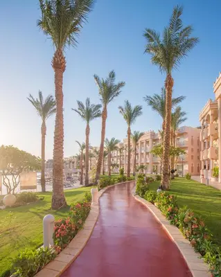 a walkway with palm trees in a resort at Pickalbatros Palace - Aqua Park Hurghada in Hurghada