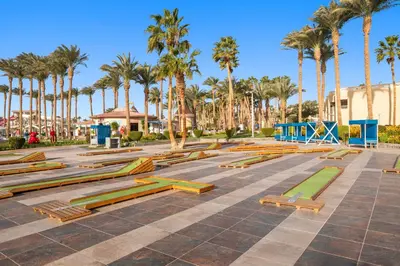 a park with wooden benches and palm trees at Beach Albatros Aqua Park - Hurghada in Hurghada