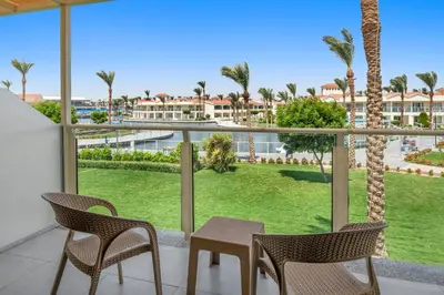 a balcony with a table and chairs and palm trees at Pickalbatros Dana Beach Resort - Aqua Park in Hurghada