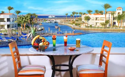 a table with a bowl of fruit next to a pool at Pickalbatros Dana Beach Resort - Aqua Park in Hurghada