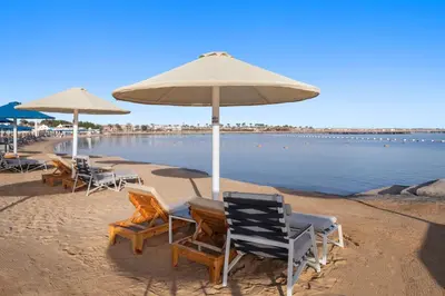 a group of chairs and umbrellas on a beach at Pickalbatros Dana Beach Resort - Aqua Park in Hurghada