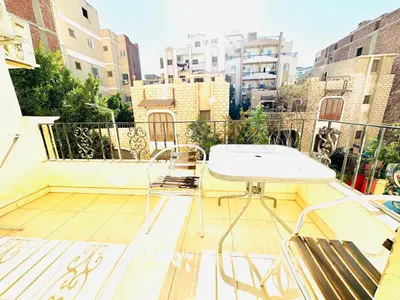 a table and chairs on a balcony with buildings at Panda Grey with balcony Hurghada center in Hurghada