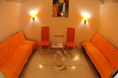 a living room with orange couches and a table and chairs at Sphinx Aqua Park Beach Resort in Hurghada