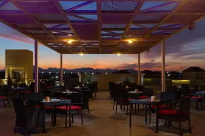 a restaurant with tables and chairs with a sunset in the background at Pickalbatros Aqua Blu Resort - Hurghada in Hurghada