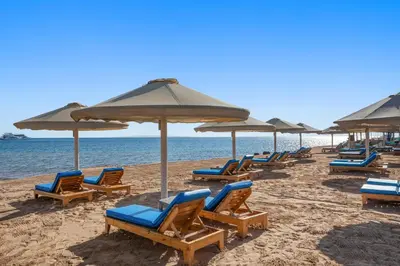 a row of chairs and umbrellas on a beach at Pickalbatros Aqua Park Resort - Hurghada in Hurghada