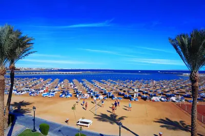 a beach with a lot of umbrellas and the ocean at Pickalbatros Alf Leila Wa Leila Resort - Neverland Hurghada in Hurghada