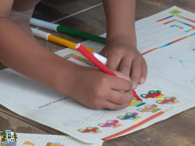a child holding a pencil and making a picture on a paper at Nubian Lotus in Aswan