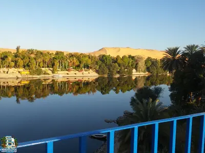 a view of a lake with palm trees and mountains at Nubian Lotus in Aswan