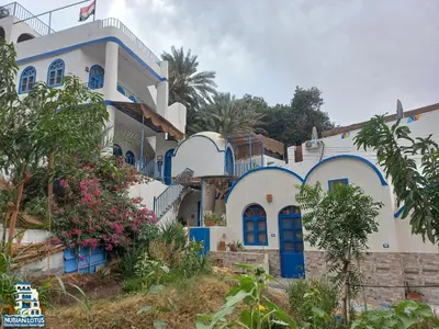 a house with blue and white walls and trees at Nubian Lotus in Aswan
