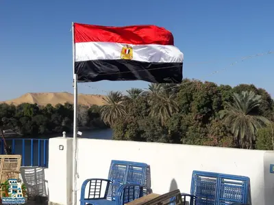a flag on top of a building with blue chairs at Nubian Lotus in Aswan