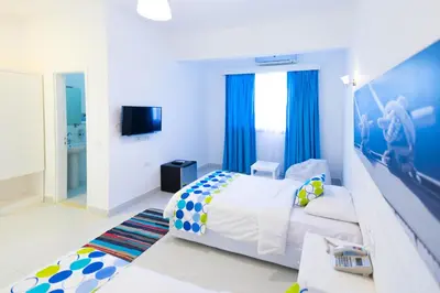 a bedroom with a white bed and blue curtains at Lagoonie Lodge & Beach in Hurghada