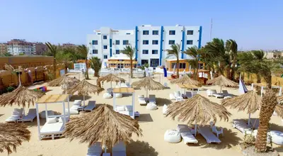 a beach with chairs and straw umbrellas and a building at Lagoonie Lodge & Beach in Hurghada