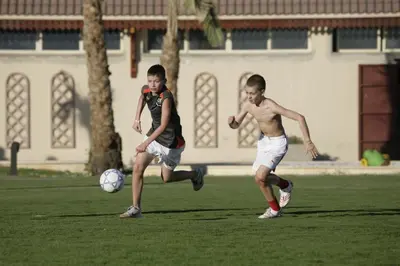 two young men playing a game of soccer on a field at Sunrise Mamlouk Palace Resort in Hurghada