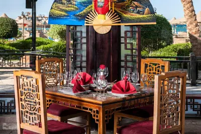 a wooden table with red napkins and wine glasses at Sunrise Mamlouk Palace Resort in Hurghada