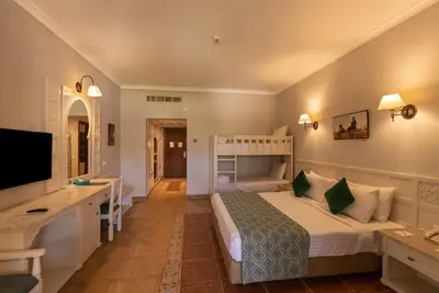 a bedroom with a bed and a desk and a television at Sunrise Mamlouk Palace Resort in Hurghada