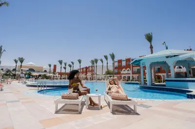 two women sitting on benches near a swimming pool at Sunrise Garden Beach Resort in Hurghada