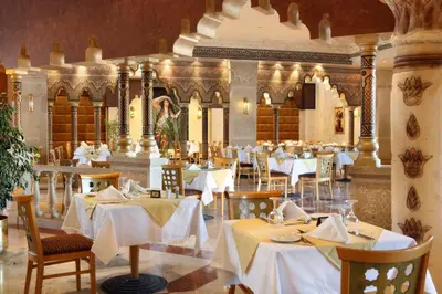 a restaurant with white tables and chairs in a room at Sunrise Garden Beach Resort in Hurghada
