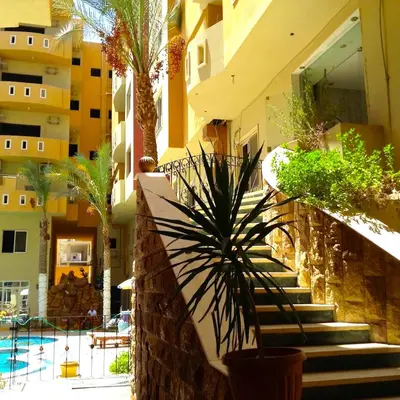 a building with stairs and palm trees next to a pool at Diamond Arabia with Wi Fi in Hurghada