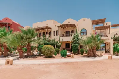 a building in the desert with palm trees at El Gouna 1 Bedroom Apartment west golf ground floor in Hurghada