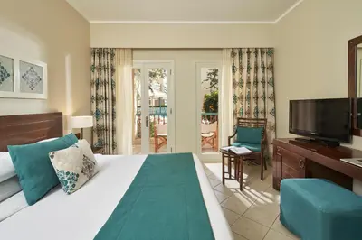 a bedroom with a bed and a television and a balcony at Mosaique Hotel El Gouna in Hurghada