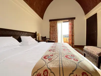 a bedroom with a white bed with a floral blanket at ONATTI Beach Resort - Marsa Alam in Quseir