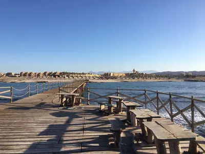 a wooden pier with picnic tables on the water at ONATTI Beach Resort - Marsa Alam in Quseir
