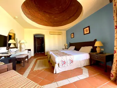 a bedroom with a large bed and a desk and a desk at ONATTI Beach Resort - Marsa Alam in Quseir