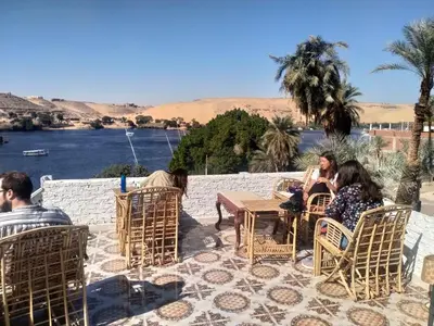 a group of people sitting at a table on a patio at Seko Kato Nile View Hostel in Aswan