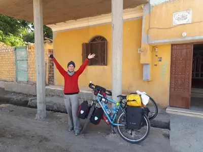 a woman standing next to a bike in front of a building at Seko Kato Nile View Hostel in Aswan