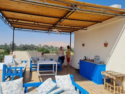 a woman standing on a patio with a table and chairs at House of Dreams apartments Luxor in Luxor