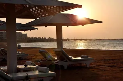 a beach with lounge chairs and an umbrella and the ocean at KaiSol Romance Resort Sahl Hasheesh - Adults Only in Hurghada