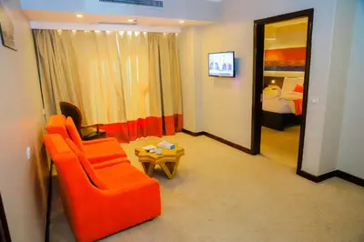 a living room with an orange chair and a table at Aswan Plaza Hotel in Aswan