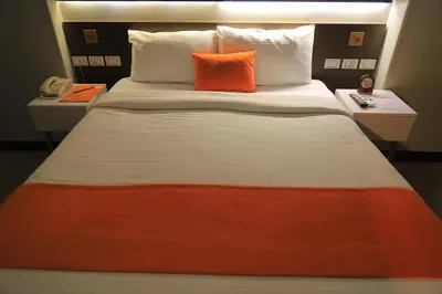 a bed with an orange pillow on top of it at Aswan Plaza Hotel in Aswan