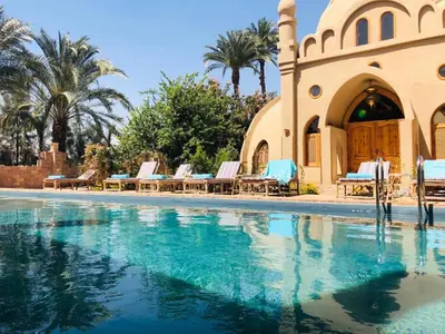 a swimming pool with chairs and a building at Embrace Hotel in Luxor