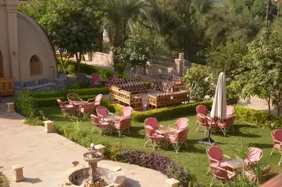 a garden with chairs and tables and an umbrella at Embrace Hotel in Luxor