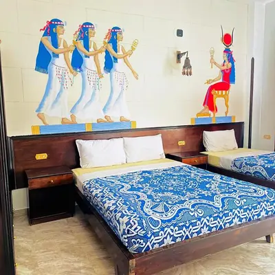 a bedroom with two beds and a painting on the wall at El Nakhil Hotel in Luxor