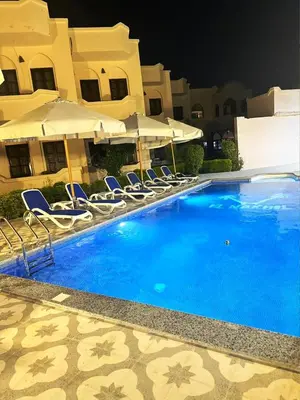 a swimming pool with chairs and umbrellas next to a building at El Nakhil Hotel in Luxor