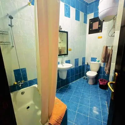 a blue tiled bathroom with a toilet and a sink at El Nakhil Hotel in Luxor