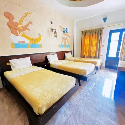 a room with three beds and a painting on the wall at El Nakhil Hotel in Luxor