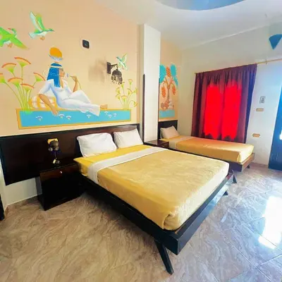 a bedroom with two beds and a painting on the wall at El Nakhil Hotel in Luxor