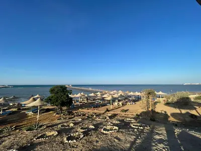 a beach with a lot of umbrellas and the ocean at Comfortable studio in hotel Karma with private beach and pools family only or female in Hurghada