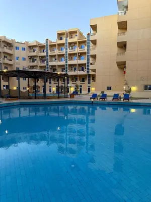 a large swimming pool in front of a building at Cozy little studio near Kite station. in Hurghada