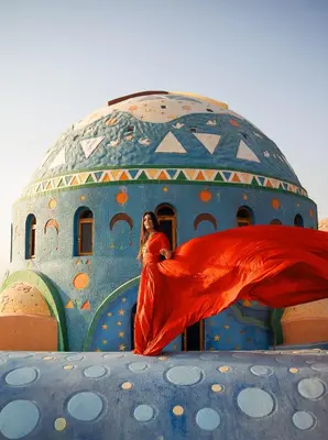 a woman in a red dress standing in front of a building at Kato Dool Wellness Resort in Aswan