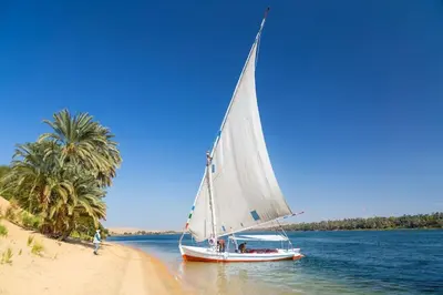 a sail boat on the water next to a beach at felouque avec toilettes in Aswan
