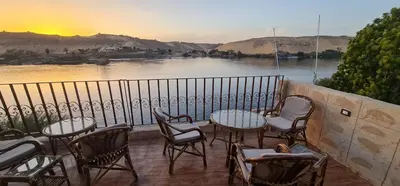 a balcony with tables and chairs and a view of a river at Meshra Katto in Aswan