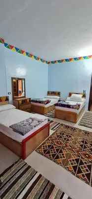 a room with three beds and rugs on the floor at Meshra Katto in Aswan